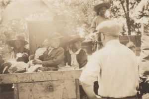 Photographic print of a white man looking at an African-American woman and several children sitting in a truck.