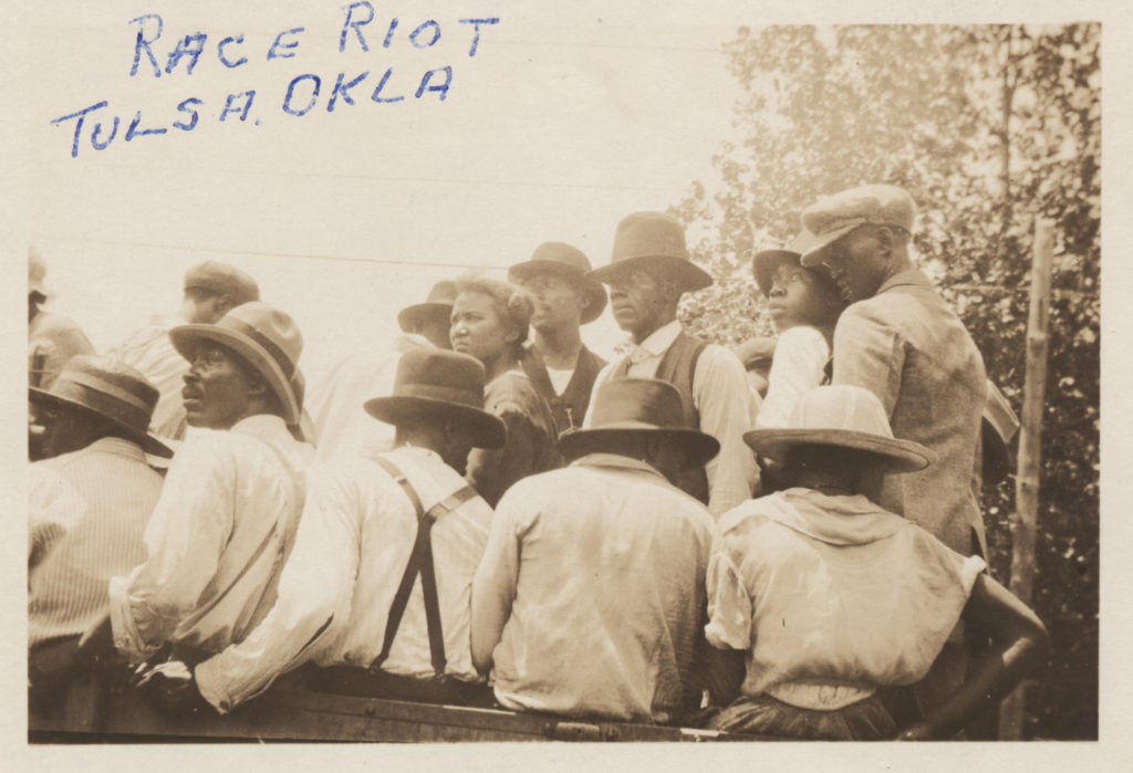 Closeup photographic print of several men and women loaded into a truck for detention and being moved into McNulty baseball park at 11th and Elgin.