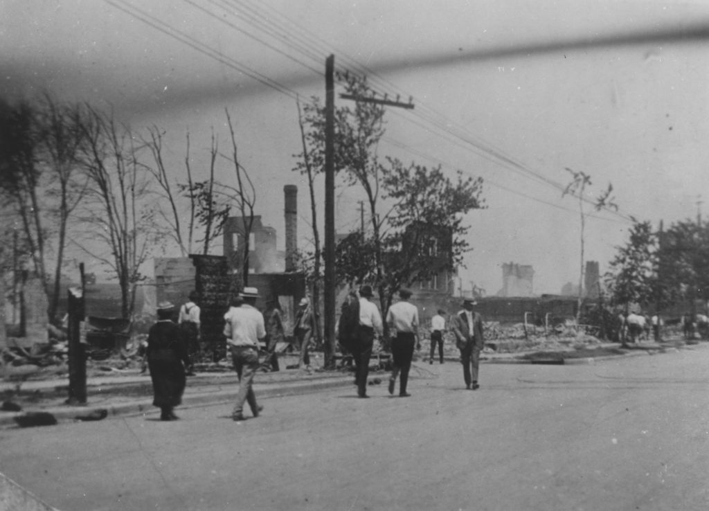 A photographic reproduction of a photo taken of people surveying the damage along Archer and Franklin. The Williams Building is in ruins. "Photographic Archives. Western History Collection, University of Oklahoma" printed on back.