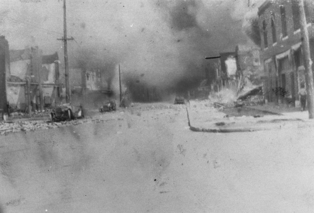 A photographic reproduction of a photo taken looking up Greenwood Ave. from Archer St. The Woods building on the right has not yet burned. "G4 of 28" written on back.