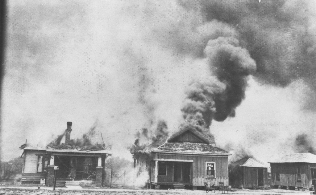 A photographic reproduction of a photo taken of houses burning during the looting. "G7 of 28" written on back.