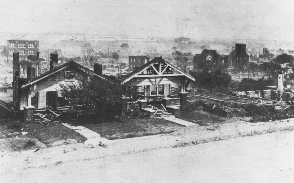 A photographic reproduction of a photo taken of the northern end of the east side of North Detroit Avenue from the top of Standpipe Hill. The houses shown are 511 N. Detroit Ave. (A.J. Smitherman), 507 N. Detroit Ave. (R. T. Bridgewater). Basement of 503 N. Detroit Ave. on right. Mt. Zion Baptist Church lies in ruins in mid-background. Booker T. Washington High School on the left. "G10 of 28" and "See F8 without" written on back.