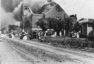 A photographic reproduction of a photo taken of the Crowd looking North up Elgin Ave. from Davenport St, watching the Mt. Zion Baptist Church burn "G11 of 28" written on back. Title supplied by cataloger.