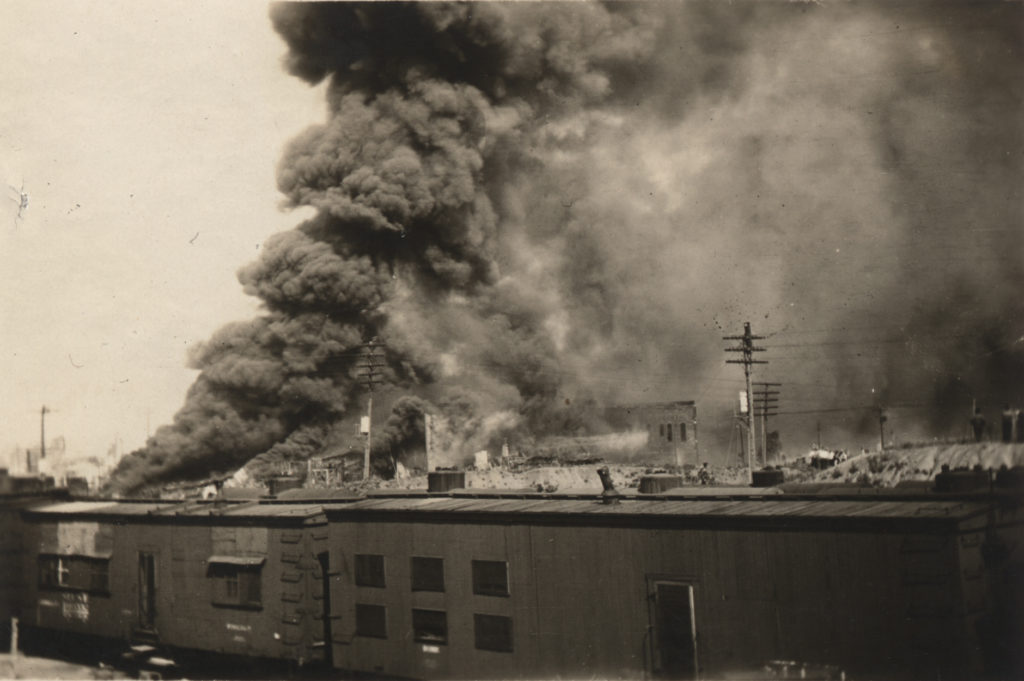A photographic print showing fires burning across the railyard.