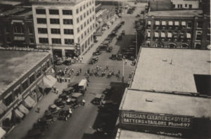 A photographic print showing the scene from the roof of the Daniel Building, and is looking north at 2nd St and Boston Ave. The detainees are to be marching to the East.