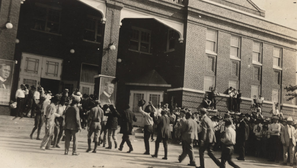 African-American detainees with their hands raised being led into the Convention Center during the Tulsa Race Riots.