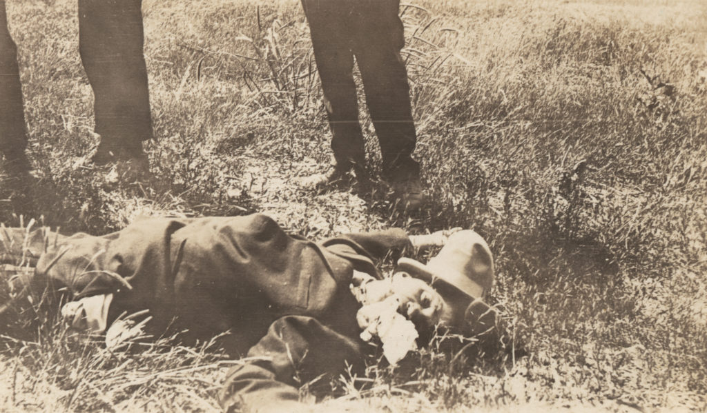 Photograph of an unidentified African-American man lying dead in the grass.