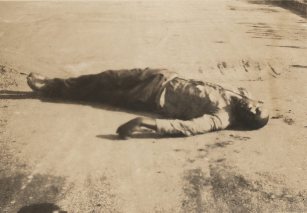 A man lies dead in the street. This victim appears in three other photographs in this collection, taken from different angles at different times (1989.005.5.6, 1989.005.5.56, and 1989.005.5.W18).