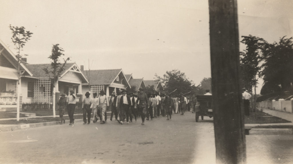 A photographic print of prisoners being marched through a street.