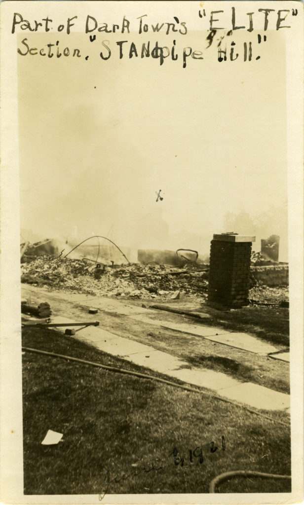 Vertical photograph of burned ruins of a house. There is an "X" written on a certain part of the photograph. Writing along the top reads "Part of Dark Town's 'ELITE' Section, 'Standpipe Hill.'"